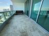 Spacious balcony featuring stone tile flooring, clear glass railing, and floor-to-ceiling sliding glass doors