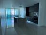 Modern kitchen featuring dark cabinetry, stainless steel appliances, a large island with a sink, and polished tile flooring