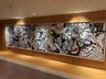 Large-scale black and white graphic artwork mounted on a wood-paneled wall, illuminated by integrated ceiling lighting