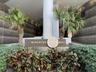 Contemporary building entrance featuring a prominent address sign and lush tropical landscaping