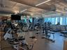 Fitness center featuring high ceilings, exposed ductwork, large windows, multiple exercise machines, and weight training equipment