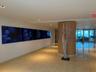 Polished stone flooring extending through a wide corridor, featuring recessed lighting and a wood-paneled column with a decorative sculpture