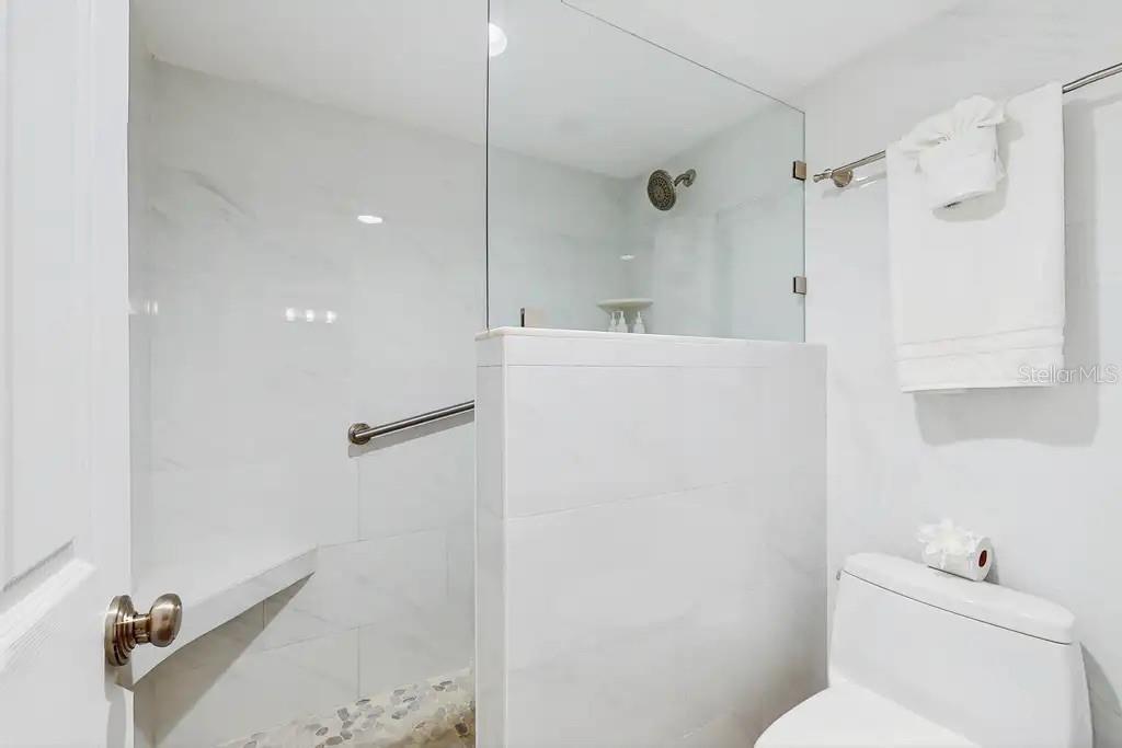LARGE WALK-IN SHOWER OFF THE PRIMARY SUITE FEATURES A BUILT IN  BENCH FOR ADDED COMFORT AND RELAXATION.