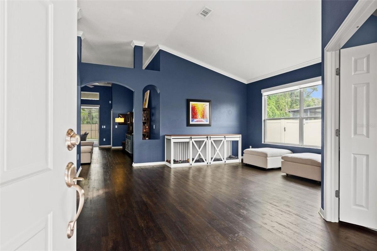Step inside to a bright, open interior where high ceilings and rich flooring immediately create a sense of space.