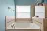 Unwind in the primary bath’s soaking tub, positioned beneath a large window for a bright, relaxing feel.