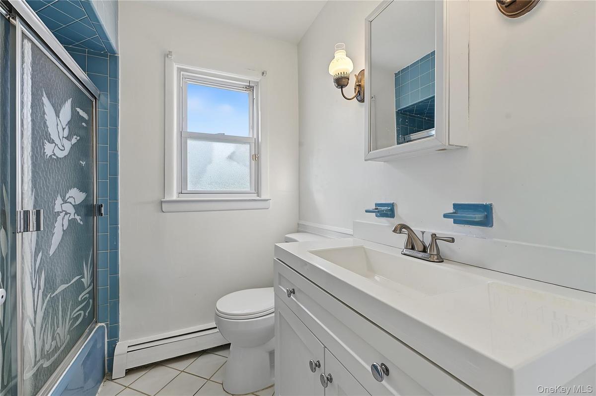 First floor bathroom with updated Vanity with integrated sink, white cabinetry and tub/shower ombo
