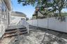 Paver patio area with a white privacy fence and exterior steps featuring brick and stone treads leading to the expansive kitchen/Dining Room