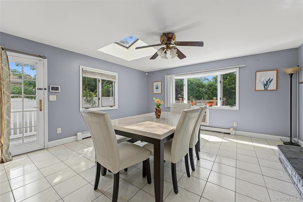 Skylight, ceiling fan,  door to the yard and garage access, tiled flooring, and multiple windows including a large bay window and wall mounted air con