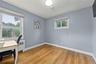 Second bedroom located on first floor with Hardwood flooring , two windows for natural light, and a white ceiling with a flush-mount light fixture