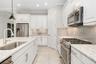 A gas range, beautiful quartz countertops and glass subway tiles are great features