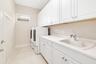 Spacious laundry room boasts an abundance of cabinetry and  counter space with sink and includes the  washer and dryer