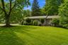 Expansive front lawn with mature trees and established landscaping