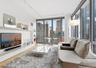 Living area featuring a city view, visible vents, floor to ceiling windows, and wood finished floors