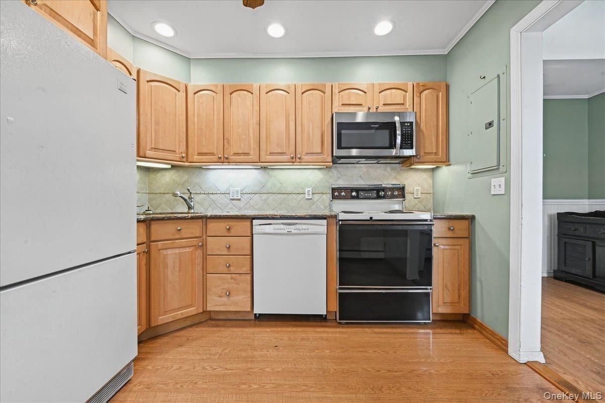 Wood-finish flooring, wood cabinetry, stainless steel microwave, and recessed lighting