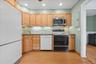 Wood-finish flooring, wood cabinetry, stainless steel microwave, and recessed lighting