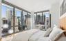 Bedroom with a wall of windows, wood finished floors, and a view of city