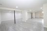 Spacious finished lower level with recessed lighting, tiled flooring, and a built-in sink cabinet