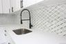 White cabinetry with matte black pulls, solid surface countertop, stainless steel undermount sink, matte black pull-down faucet, and geometric pattern