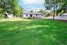 Expansive green lawn with mature trees and a privacy fence