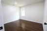Recessed ceiling lighting illuminates wood-finish flooring and a single window with white trim