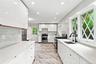 Kitchen featuring white flat-panel cabinetry, white countertops, stainless steel appliances, black fixtures, and patterned flooring