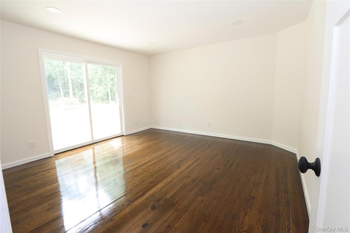 Hardwood flooring, recessed lighting, sliding glass door, white trim, and a matte black door handle