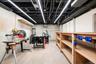 Concrete block walls with a concrete floor, featuring built-in wooden shelving and overhead linear lighting fixtures