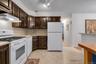 Kitchen featuring brown cabinetry, light countertops, white appliances, and tiled flooring