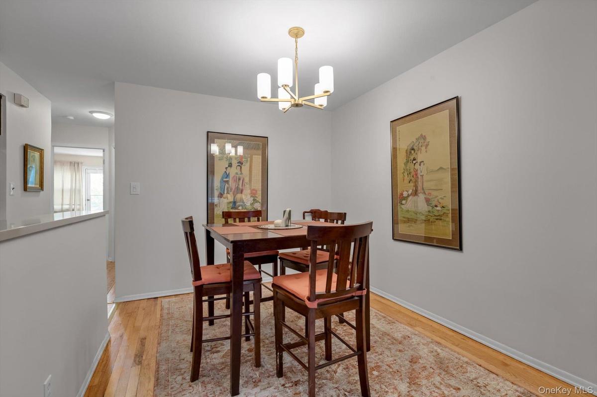 Hardwood flooring, neutral wall paint, and a contemporary chandelier