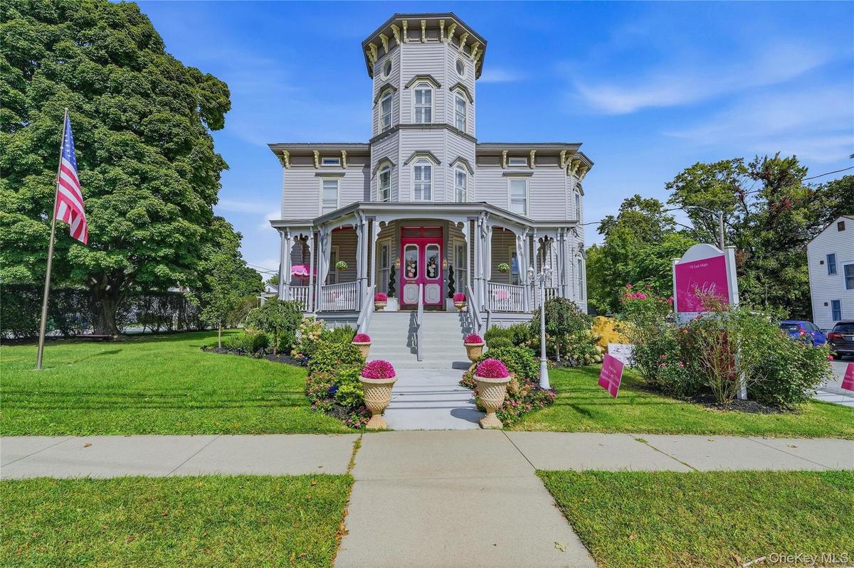 Victorian-style exterior with a prominent turret, wraparound porch, and vibrant landscaping