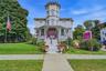 Victorian-style exterior with a prominent turret, wraparound porch, and vibrant landscaping