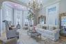 Hardwood flooring, bay window with plantation shutters, coffered ceiling, ornate chandelier, and decorative wall mirrors