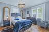 Light-colored wood-finish flooring, two large windows with blinds, crown molding, and a decorative chandelier