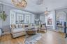 Wood-finish flooring throughout, bay window with plantation shutters, decorative ceiling medallions, and a decorative beaded chandelier