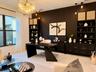 Custom built-in desk with integrated storage and display cabinetry, positioned opposite the office seating area.