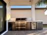 Covered outdoor kitchen equipped with built-in grill, storage, and counter space for year-round outdoor entertaining.