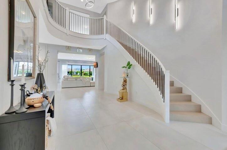 Dramatic entry foyer featuring a sweeping staircase, soaring ceilings, and abundant natural light.