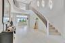 Dramatic entry foyer featuring a sweeping staircase, soaring ceilings, and abundant natural light.