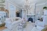 Ornate chandelier, decorative fireplace with stone surround, crown molding, and light wood-finish flooring