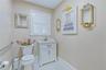 White shaker-style vanity with a solid surface countertop and gold-tone faucet