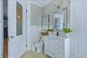 White vanity with integrated sink, black single-handle faucet, and mirrored storage cabinet