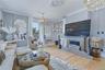 Light wood-finish flooring, decorative ceiling medallion, sliding glass door, stone fireplace surround, and crown molding