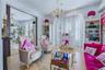 Hardwood flooring, ornate chandelier, decorative crown molding, built-in shelving, and large windows with plantation shutters