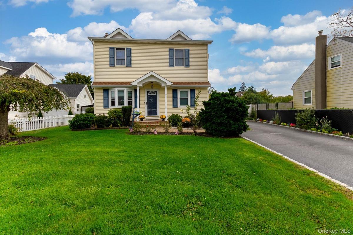 Two-story residence with dormer windows, a covered front entry, and a paved driveway