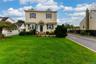 Two-story residence with dormer windows, a covered front entry, and a paved driveway