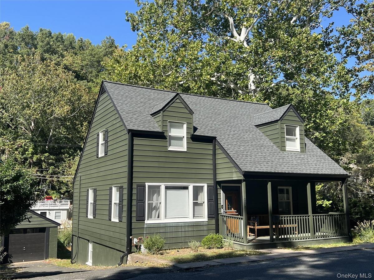 View of front of home featuring covered porch and a shingled roof
