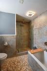 Walk-in shower with glass enclosure, integrated bathtub, and full-height wall tiling