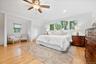 Primary Bedroom Bright interior with wood-finish flooring, a ceiling fan, recessed lighting, and a large arched window