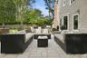Expansive stone patio with modular seating, stone retaining walls, and surrounding mature trees