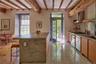 Kitchen with open shelves, wall chimney exhaust hood, backsplash, a breakfast bar area, and beam ceiling